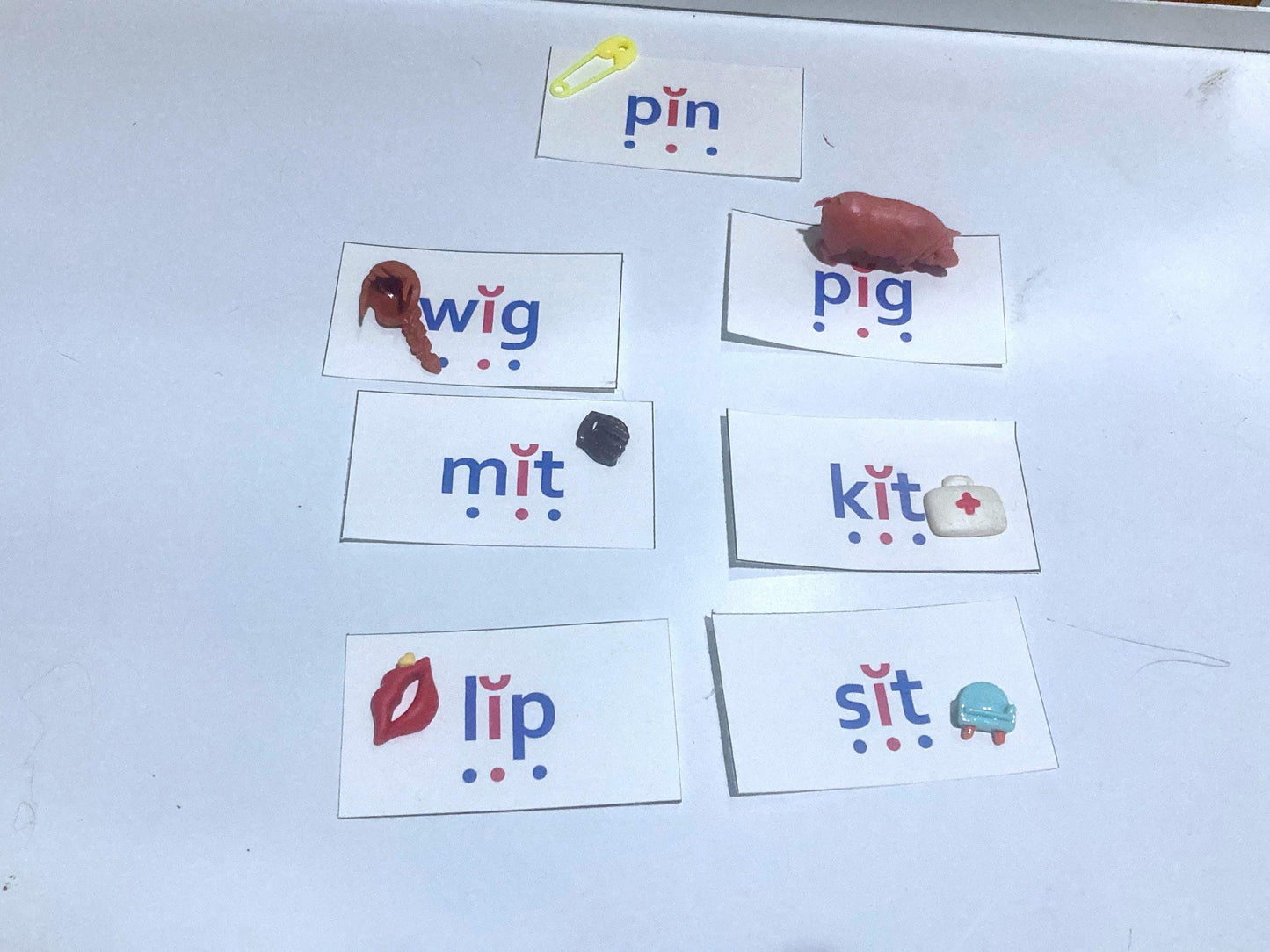 CVC, short i Flashcards with phonetic spellings and  miniature toys on a white table.