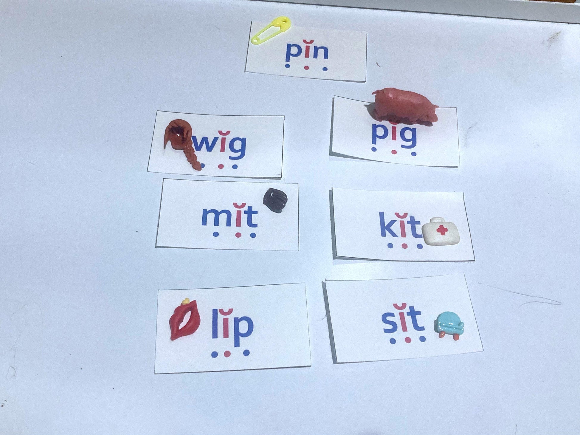 CVC, short i Flashcards with phonetic spellings and  miniature toys on a white table.