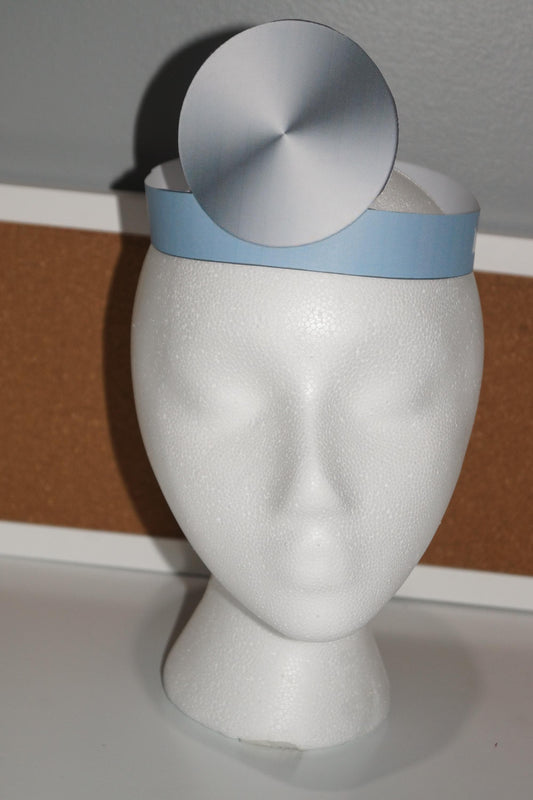 Printable doctor’s hat with blue band and silver head mirror displayed on a white mannequin head, perfect for community helper and dramatic play centers.