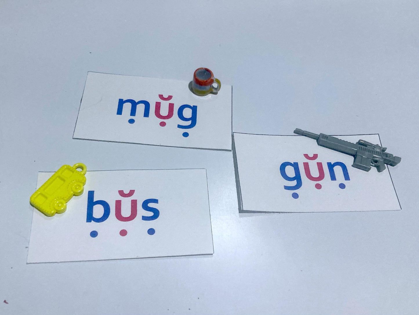 Three cards with colorful letters on a white background, each accompanied by a small toy.