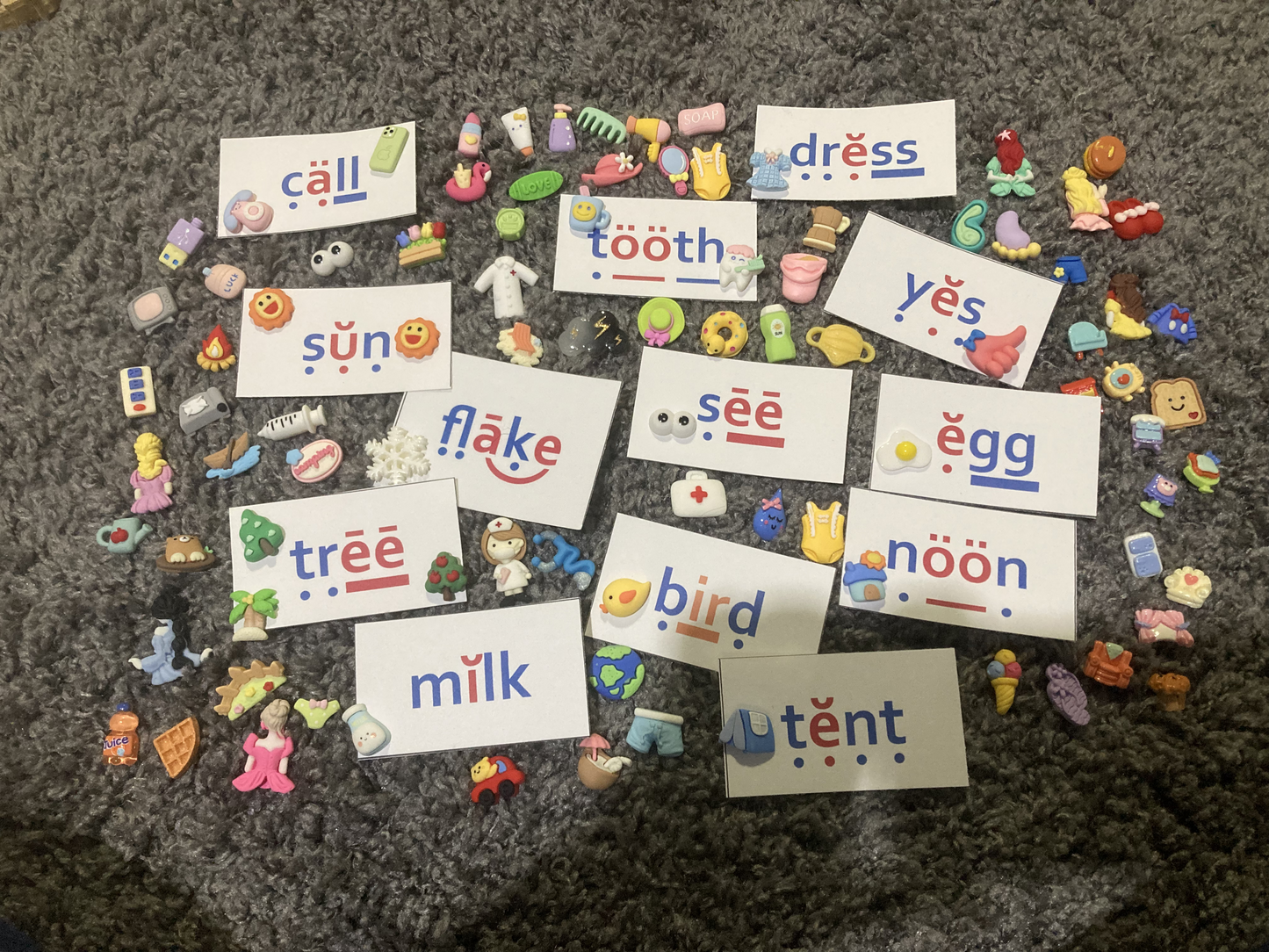 Colorful educational cards with phonetic spellings on a textured surface
