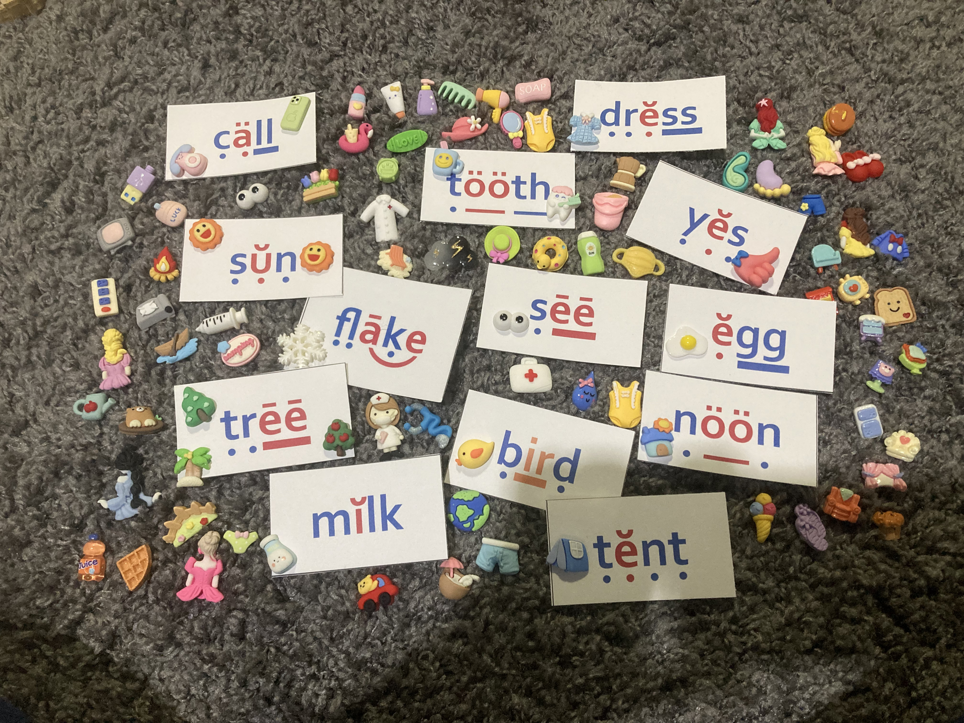 Colorful educational cards with phonetic spellings on a textured surface